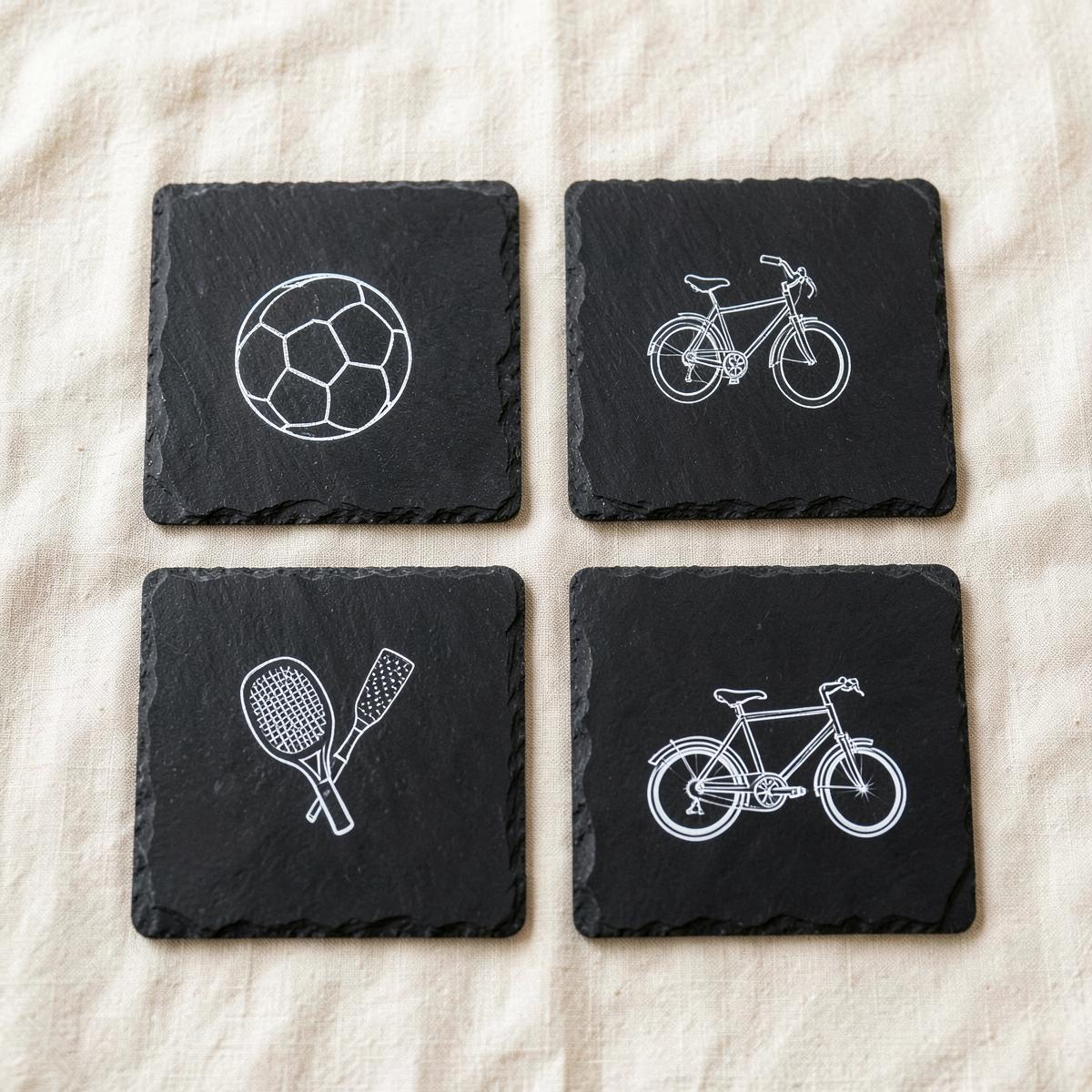 Set de cuatro posavasos de pizarra grabados con balón, bicicleta y palas de pádel